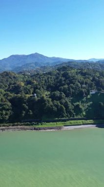 Dikey hava manzarası, botanik bahçesi ve Batumi 'deki demiryolu. 4K İHA Gürcistan seyahat görüntüleri, kıyı şeridi boyunca yemyeşil alanlar, yoğun astropikal bitki örtüsünün yanında giden tren rayları.