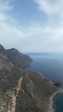Dikey dron atışı: Gramvousa adası uçurumlarının yüksek irtifa görüntüsü, derin mavi Akdeniz, Girit doğası. Yüksek kalite 4k görüntü