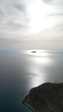 Dikey dron atışı: Gramvousa adası uçurumlarının yüksek irtifa görüntüsü, derin mavi Akdeniz, Girit doğası. Yüksek kalite 4k görüntü