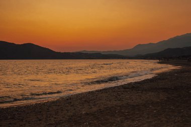 Fotoğraf, güneşin suyun üzerinde batan ılık renklerini yakalar ve barışçıl ve romantik bir atmosfer yaratır. Seyahat, tatil ve rahatlama temaları için ideal