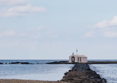 Resimli inzivaya çekilme: Ege 'ye uzanan dar bir kaya iskelesinde beyazlatılmış şapel. Çekici sahne sükunetin, deniz tarihinin ve kıyıların engebeli güzelliğinin özünü yakalar.