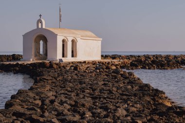 Resimli inzivaya çekilme: Ege 'ye uzanan dar bir kaya iskelesinde beyazlatılmış şapel. Çekici sahne sükunetin, deniz tarihinin ve kıyıların engebeli güzelliğinin özünü yakalar.