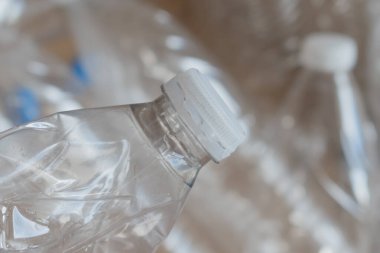 Birçok temiz plastik su şişesi geri dönüşüm için hazırlanan bir yerde karton bir kutuya konur. Sahne, çevre dostu bir çabayla şişelerin tekrar kullanılmaya hazır olduğunu gösteriyor..