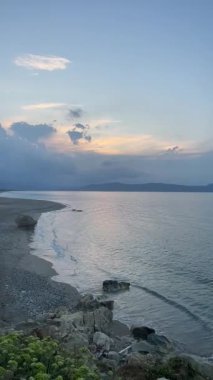 Dikey çekim: Kayalık sahilli boş kumlu sahil manzarası ve gün batımında sakin deniz dalgaları, Girit