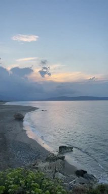 Dikey çekim: Kayalık sahilli boş kumlu sahil manzarası ve gün batımında sakin deniz dalgaları, Girit