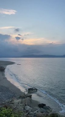 Dikey çekim: Kayalık sahilli boş kumlu sahil manzarası ve gün batımında sakin deniz dalgaları, Girit