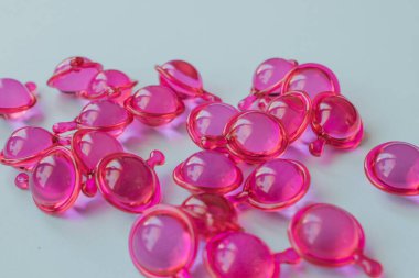 Bir sürü parlak pembe saç tedavi kapsülünün aşırı yakın plan makro görüntüsü. Odaklanmış önplan, derin su ve sağlığı simgeleyen zengin yağ ve yansıtıcı dokuyu vurgular
