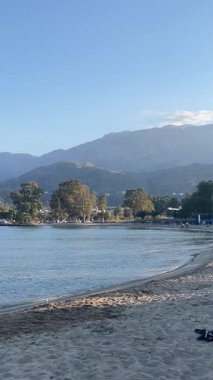 Georgioupolis 'te sakin bir öğle yemeği: sakin turkuaz deniz, altın kum, güneşli gökyüzü ve ferah bir deniz manzarasında çekilmiş rahat sahil hayatı. Yüksek kalite 4k görüntü