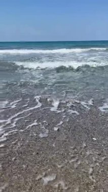 Dikey çekim: beyaz köpüklü deniz dalgaları çakıl taşlı plajları siliyor, uzak dağ sıralarına yayılıyor, Girit kıyıları