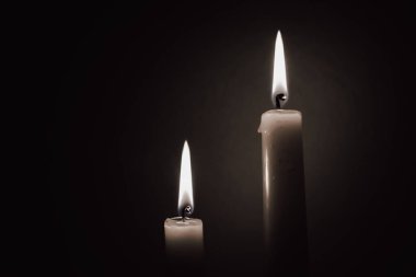 Siyah-beyaz şeklinde yanan iki mum, yas tutma konsepti ya da enerji kesintisi arkaplanı, karanlıkta hafıza ve ışığın sembolü.