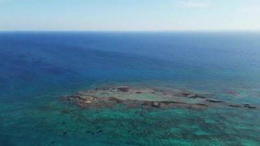 Elafonisi 'deki turkuaz göllerin insansız hava aracı görüntüsü. Kristal su boyunca kayaların ve karanlık resiflerin detaylı sualtı mozaiği. El değmemiş Akdeniz sahili arka planı. Yüksek kalite 4k görüntü