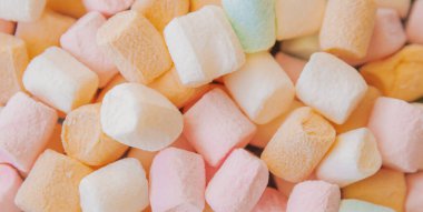 Renkli şekerlemelerin üst görüntüsü yumuşak bir şeker dokusu yaratıyor. Pastel pembe ve beyaz tatlılar tozlu yüzey ile tasarım için tatlı kadife bir arka plan sunar.