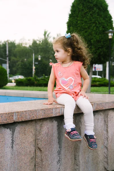 Pequena menina sentada no parque — Fotografia de Stock