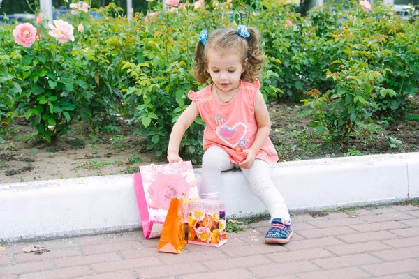 Adorable niña pelo rizado con coloridas bolsas de compras — Foto de Stock