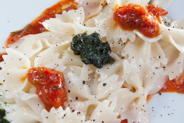 Фарфалле Паста с песто и томатным соусом на белой тарелке — стоковое фото