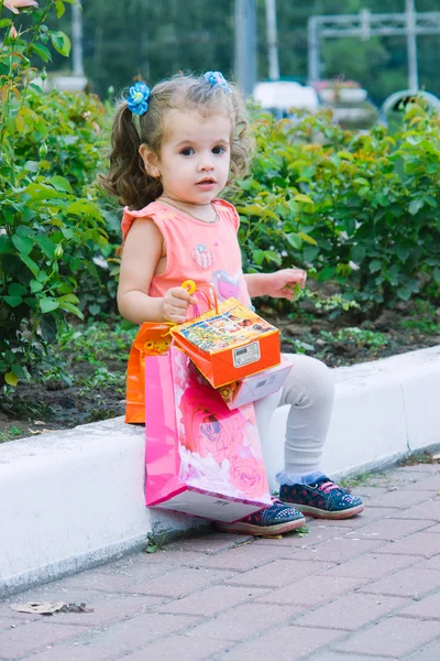 Adorable niña pelo rizado con coloridas bolsas de compras — Foto de Stock