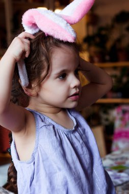 Küçük kız kafasında tavşan kulaklarıyla eğleniyor.