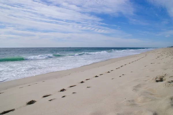 Huellas en una playa de arena junto al océano . — Foto de Stock