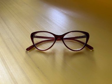 Sarı Tahta Masa 'da Koyu Kırmızı Kedi Gözlüklü Gözlük