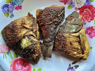 Golden Brown Crispy Deep Fried Marinated Fish Served on a Floral Patterned Ceramic Plate