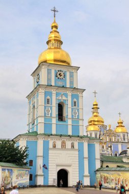 St. Michael manastırının giriş meydanından geçen ziyaretçiler, canlı mavi duvarları, altın kubbeleri ve süslü dini sanat eserleriyle karakterize ediliyor..