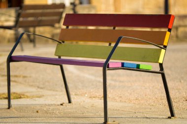 LGBT gökkuşağının renklerine boyanmış ahşap bir bankın yan görüntüsü.
