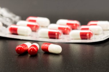 Arka planda su toplaması olan kırmızı ve beyaz haplara yakın plan, telif alanı ve siyah arkaplan