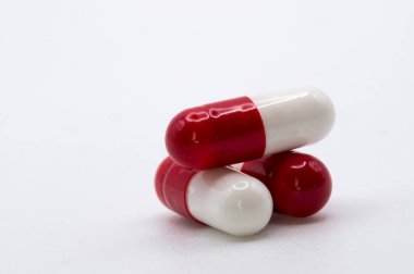 Beyaz arka plan ve telif alanı, sağlık hizmetleri kavramına sahip birkaç kırmızı ve beyaz hapın ayrıntıları.