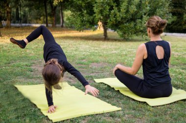 Yoga yaparken genç annesini taklit eden bir çocuğun komik fotoğrafı.