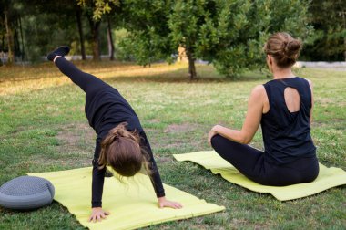 Güzel anne ve oğlu dışarıda yoga yapıyorlar, açık hava sporu konsepti.