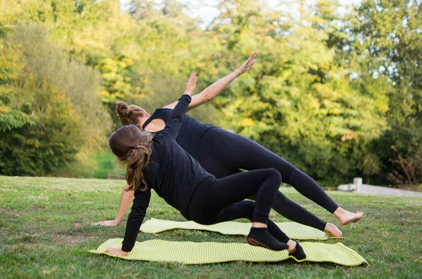 Siyah dar elbiseli genç anne oğluyla yoga yapıyor.