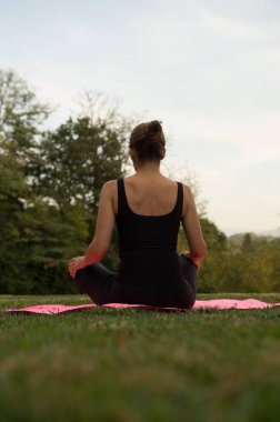 Siyah giyinmiş güzel bir kadın piyango pozisyonu, spor ve sağlık konsepti ile meditasyon yapıyor.