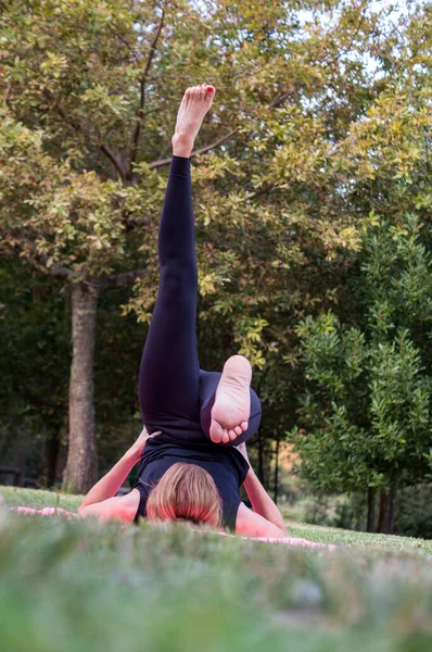 Bacağı kalkık bir mankenin fotoğrafı bahçesindeki yoga dersinde esneme hareketleri, sağlıklı alışkanlıklar konsepti.