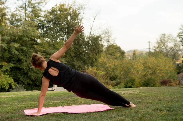 Parkta yoga yapan genç bir kadın, sağlıklı ve sağlıklı bir vücut.