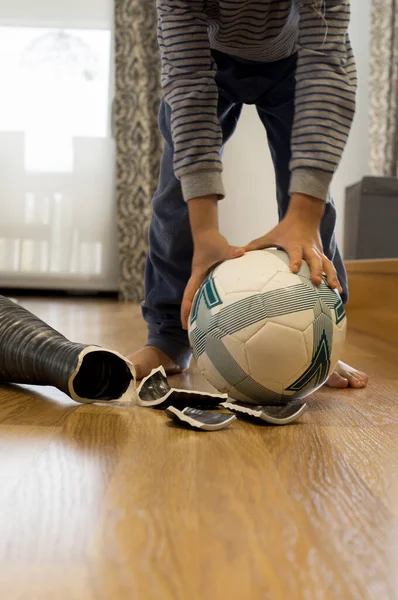 Yeni kırdığı vazonun önünde balo tutan odaksız bir çocuk, eğitim ve yaramazlık kavramı.