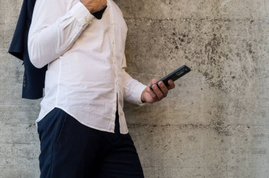 Takım elbiseli bir işadamı akıllı telefon kullanıyor.