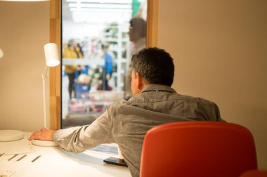 Ofisteki bir masadan Pencereden Dışarı Bakan Adam