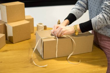 Ahşap bir masanın üzerinde karton bir kutuyu açan ellerin yakın çekimi. Müşteri tecrübesi, ürün açma veya e-ticaret geri dönüşleri kavramı.