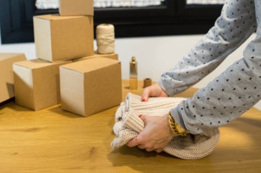 Moda mağazasının günlük iş akışını gösteren bir kutu yığınının yanında sipariş veren bir kadının omuz üstü görüntüsü.