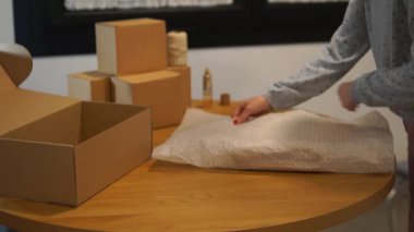 Bir satıcı yüksek kaliteli bir ikinci el kazağı koruyucu çevre dostu mendil kağıdına katlar, kalite kontrolü ve bakımı vurgular..