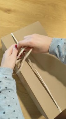 Dönüştürülmüş mukavva ve doğal kağıt sicim gibi çevre dostu materyallerle nakliye için bir paket hazırlayan kişinin yakın çekimi