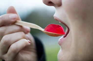 Kırmızı jelatin tatlısını kaşıkla yiyen biri.