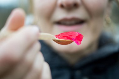 Bir insan, ultra işlenmiş gıdalar ve potansiyel endokrin sistem müdahalesi arasındaki bağlantıyı temsil eden bir kaşık dolusu kırmızı jöle tutar..