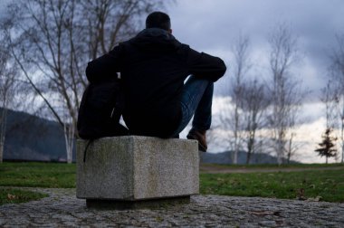 Sırt çantalı bir adam parkta durmuş ufka bakıyor.