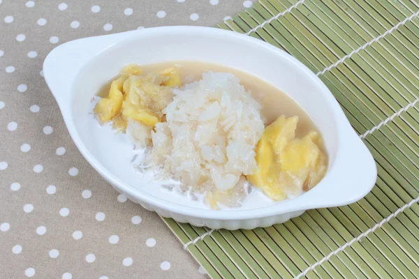 Durian en crema de coco con arroz tailandés pegajoso rematado leche de coco. Vista lateral . — Foto de Stock