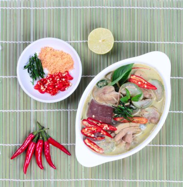 Hindistan cevizi sütünde yeşil tavuk köri kıyılmış kurutulmuş karides olarak garnitür ile servis, dilimlenmiş kırmızı biber, dilimlenmiş kaffir kireç yaprakları ve gri yeşil limon.