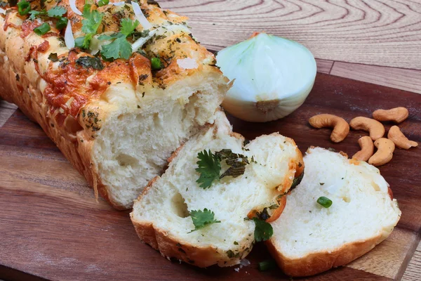 Hausgemachtes Spinatbrot mit Zwiebelhälften und Cashewnüssen auf Metzgerei serviert. Seitenansicht. — Stockfoto