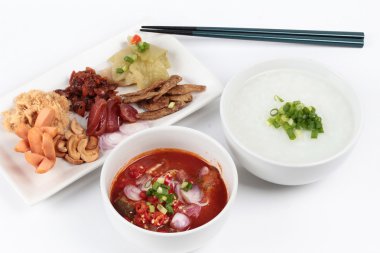 Pirinç gruel ve beyaz arka plan üzerinde garnitür. (Kurutulmuş rendelenmiş domuz eti, Çin sosis, gevrek balık, sosis, kızarmış bebek istiridye, dilimlenmiş kırmızı soğan, turşu Çin lahanası, Baharatlı sardalya salatası ve arpacık )