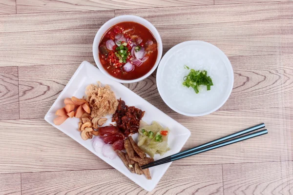 Pirinç gruel ve ahşap garnitür. (Kurutulmuş rendelenmiş domuz eti, Çin sosis, gevrek balık, sosis, kızarmış bebek istiridye, dilimlenmiş kırmızı soğan, turşu Çin lahanası, Baharatlı sardalya salatası ve arpacık )