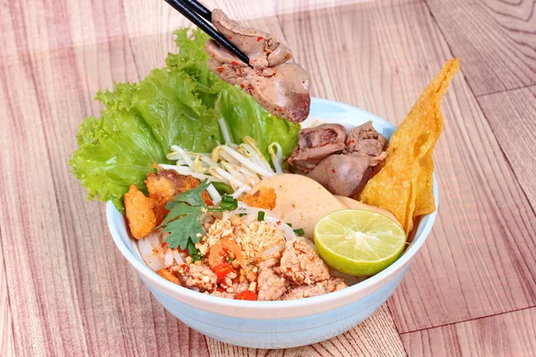 Noodle with tom yam topped with minced pork,chicken liver,wonton,shrimp ,chili. and green lemon on wood — Stock Photo, Image